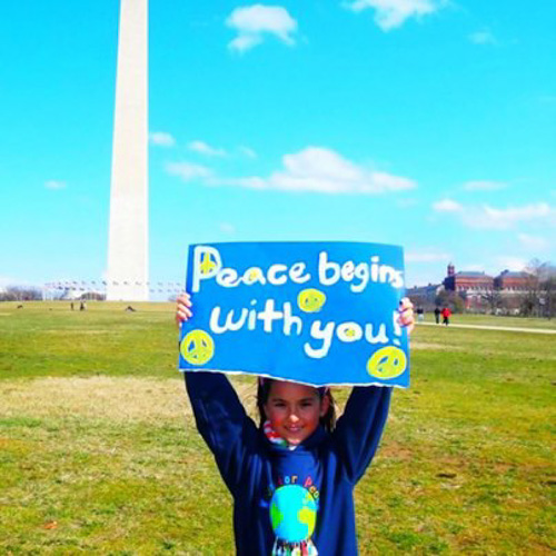 Child holding Peace Begins With You sign